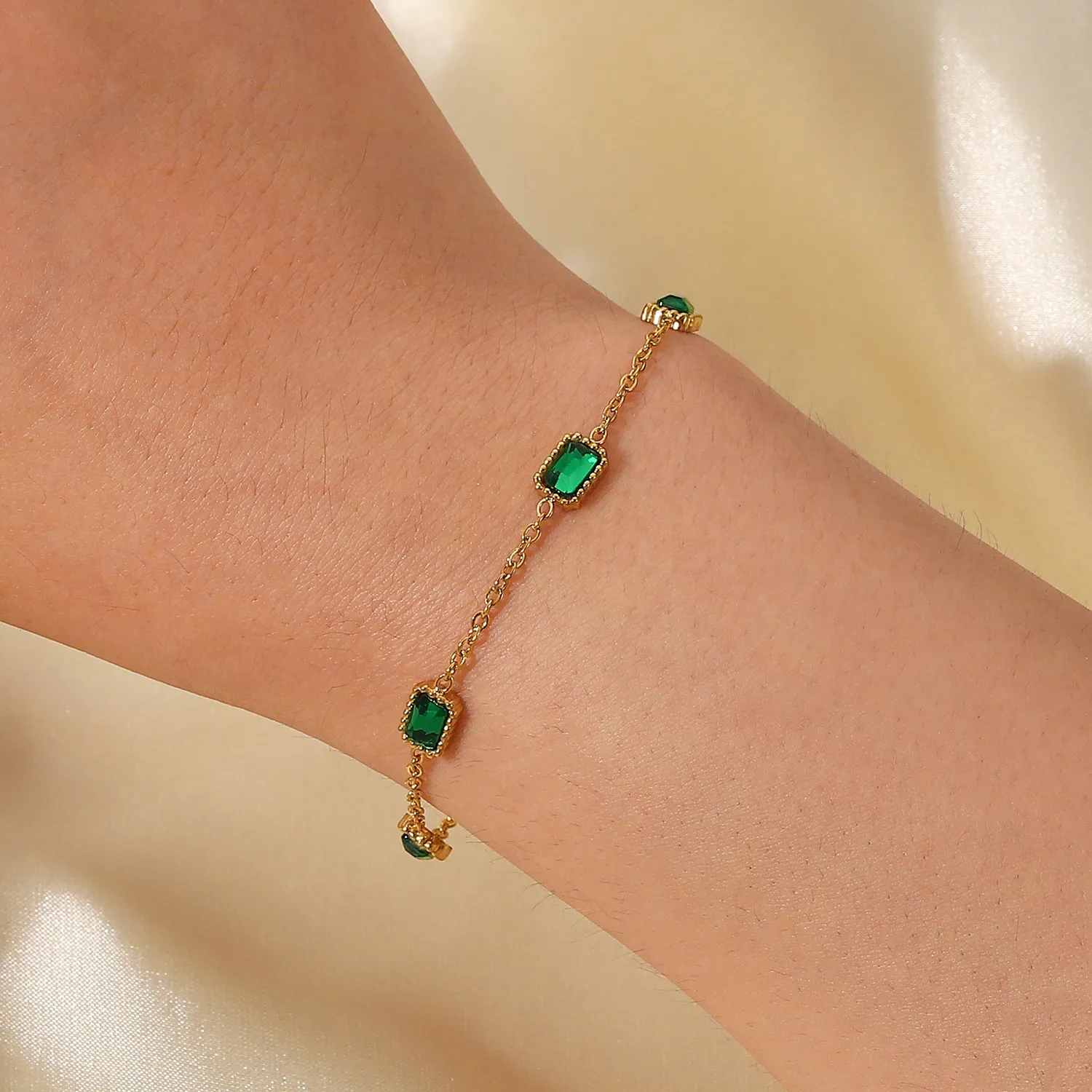 Bracciale minimalista con zirconi verdi a spina di pesce e catena Figaro intrecciata con ciondoli di smeraldo_voghion.com