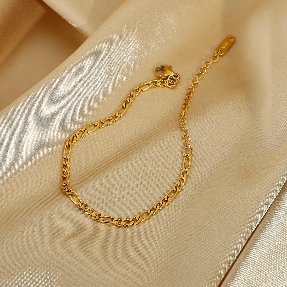 Bracciale minimalista con zirconi verdi a spina di pesce e catena Figaro intrecciata con ciondoli di smeraldo_voghion.com